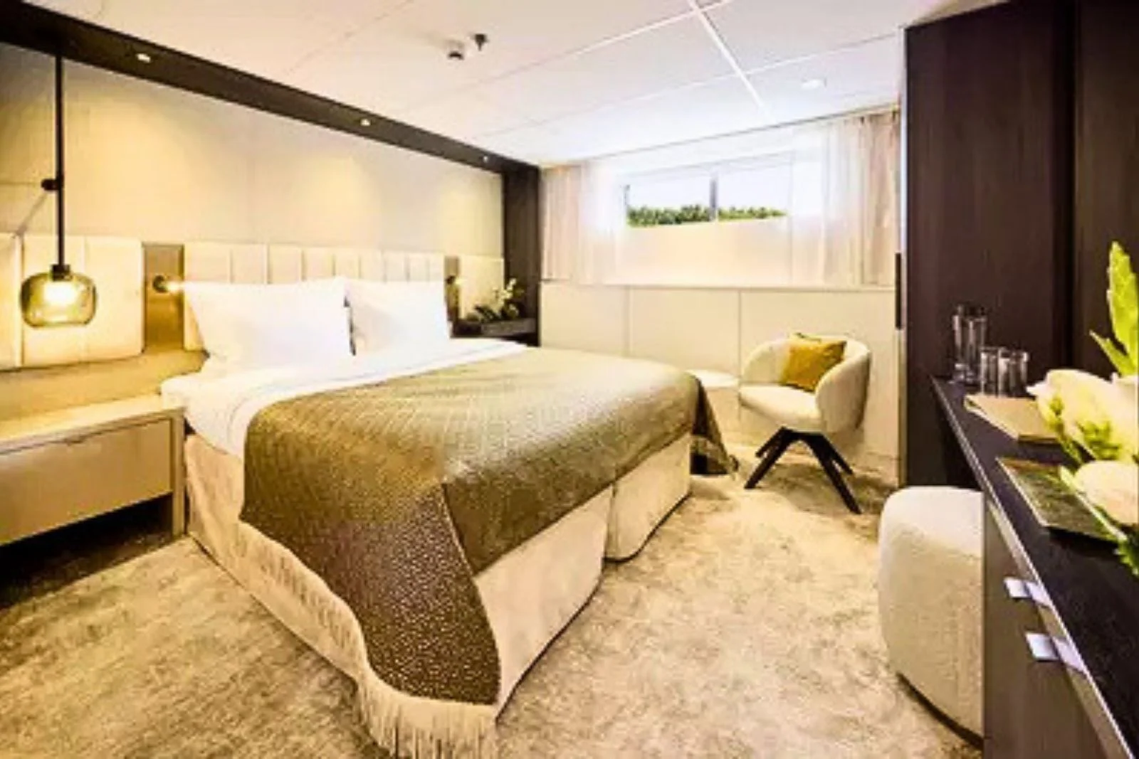 A river cruise cabin with a queen bed and a large fixed window above the riverbank