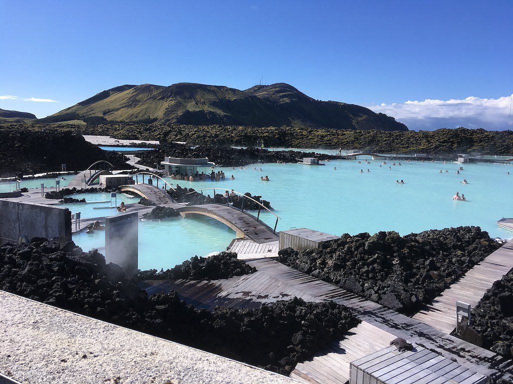 Bathers relaxing in the milky-blue water of Iceland's Blue Lagoon, with wooden walkways over black lava rock
