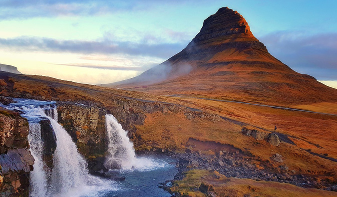 Kirkjufell mountain rising above Kirkjufellsfoss waterfall in golden evening light