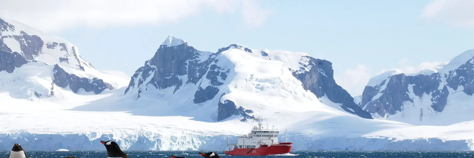 Snowy peaks along the Antarctic coastline with a ship offshore