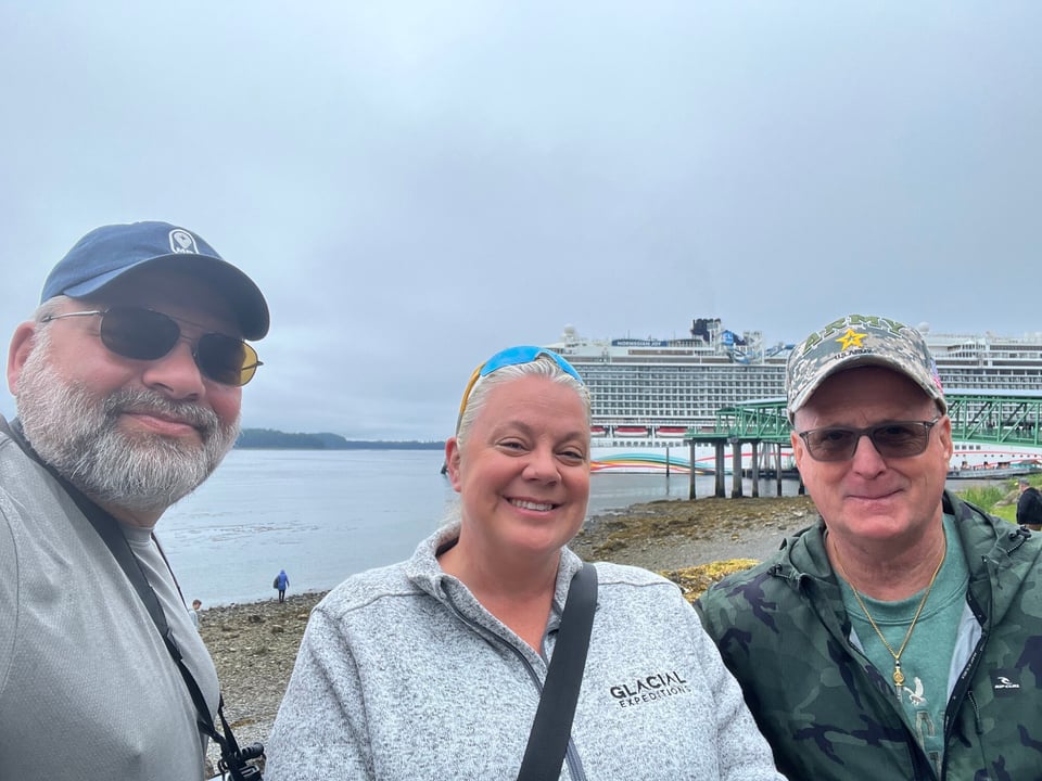 Journey with Erika travelers posing together at an Alaskan cruise port with the docked Norwegian Joy behind them