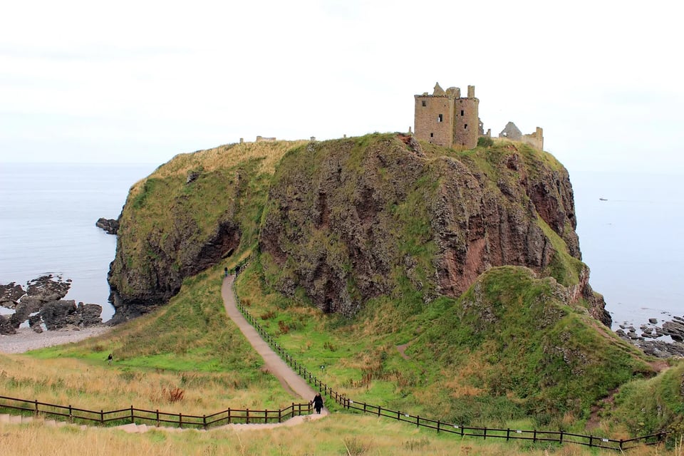 The ruins of Dunnottar Castle on a grassy clifftop above the sea in Scotland
