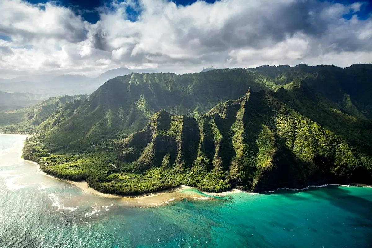 The green, ridged cliffs of the Nā Pali Coast above turquoise water on Kauai