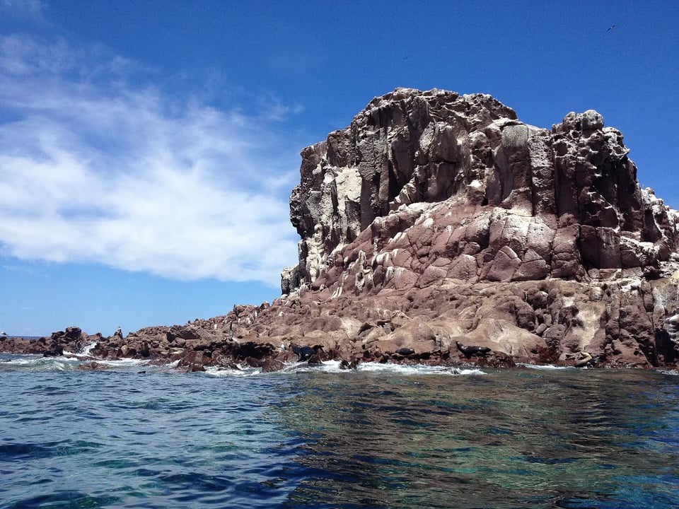 A rocky sea lion colony island rising from clear blue water in the Sea of Cortez, Baja California