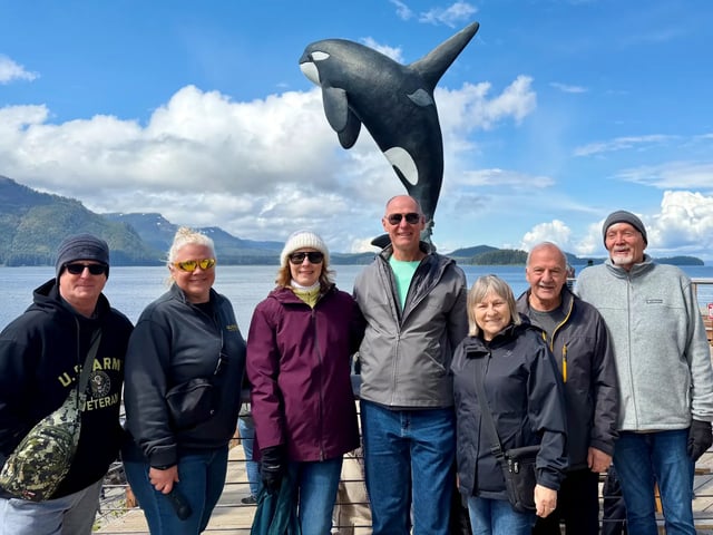 Journey with Erika travelers standing together in front of an orca statue on the Alaska waterfront