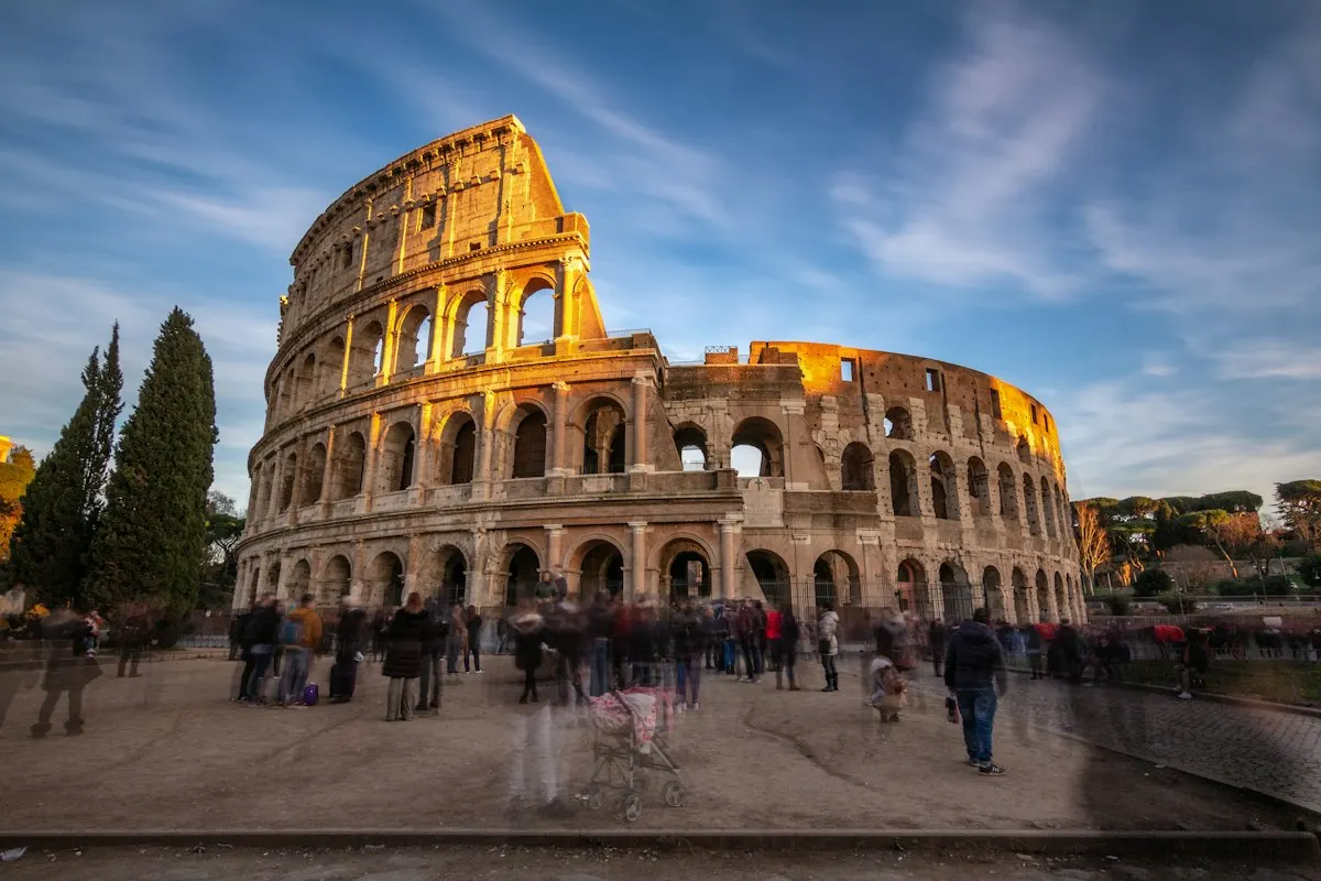 The Colosseum in Rome glowing at sunset with visitors in front